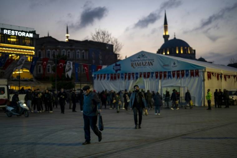 Des fidèles repartent après avoir reçu un repas pour l'iftar offert par la municipalité d'Istanbul, pendant le mois du ramadan, le 15 mars 2024 en Turquie ( AFP / Yasin AKGUL )