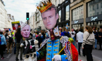 Un manifestant porte un masque du président Emmanuel Macron et tient une peluche représentant le Premier ministre Michel Barnier lors d'un rassemblement contre le gouvernement "Macron-Barnier" à l'appel de la France Insoumise, le 21 septembre 2024 à Paris ( AFP / Dimitar DILKOFF )