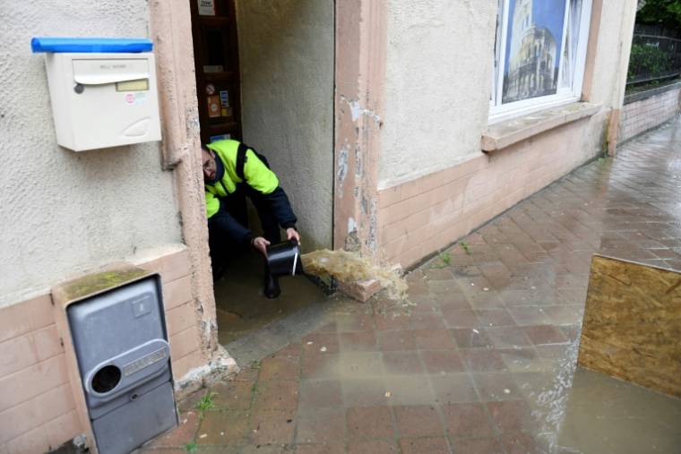 Un habitant vide sa maison inondée avec un seau, le 17 mai 2024 à Boulay, en Moselle ( AFP / Jean-Christophe VERHAEGEN )