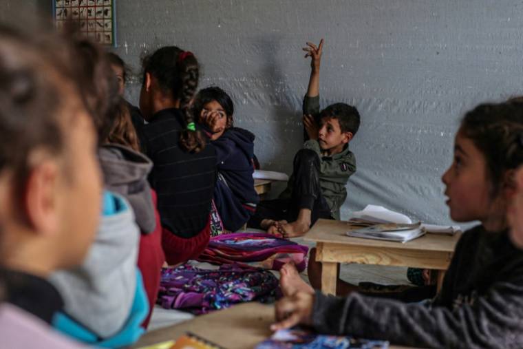Des enfants suivent un cours le 27 mars 2024 dans une tente d'un camp de déplacés palestiniens à Rafah, dans le sud de la bande de Gaza, où une guerre oppose Israël au mouvement islamiste Hamas ( AFP / SAID KHATIB )