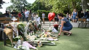 Une femme dépose des fleurs dans le parc "Les jardins de l'Europe", le lendemain d'une attaque au couteau, le 9 juin 2023 à Annecy ( AFP / OLIVIER CHASSIGNOLE )