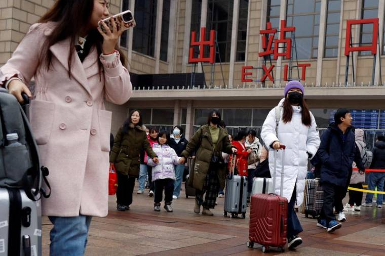 Des voyageurs marchent avec leurs bagages à l'extérieur de la gare de Pékin pendant la Fête du Printemps