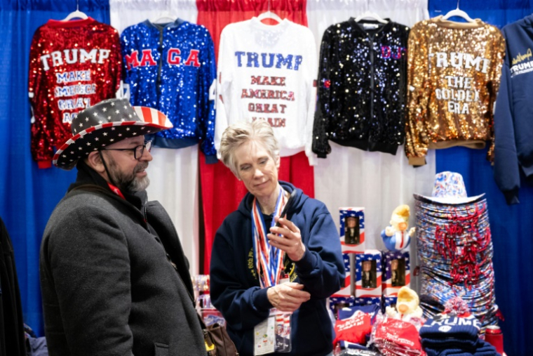 Un participant de la convention CPAC essaie un chapeau aux couleurs du drapeau américain, à National Harbor, près de Washington, le 20 février 2025 ( AFP / SAUL LOEB )