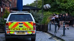 Un manifestant jette un fût de bière sur une voiture de police, à Bristol, le 3 août 2024 ( AFP / JUSTIN TALLIS )