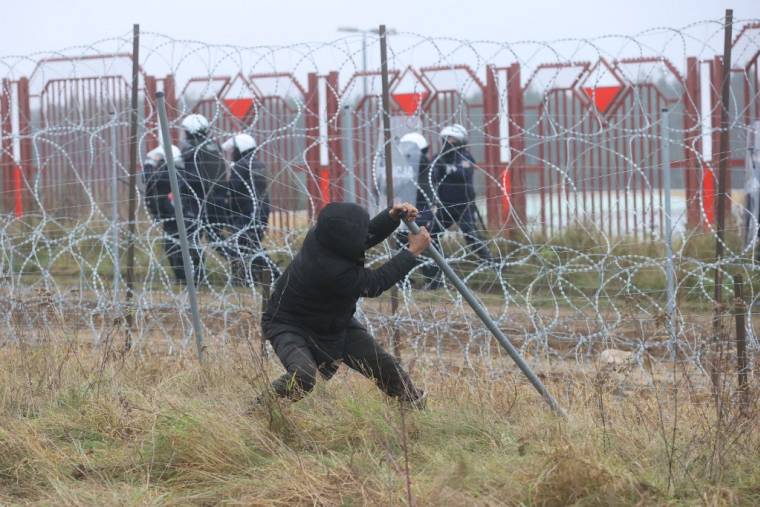 Un migrant tentant de détruire une barrière à Grodno, au Bélarus, le 16 novembre 2021. ( BELTA / LEONID SHCHEGLOV )