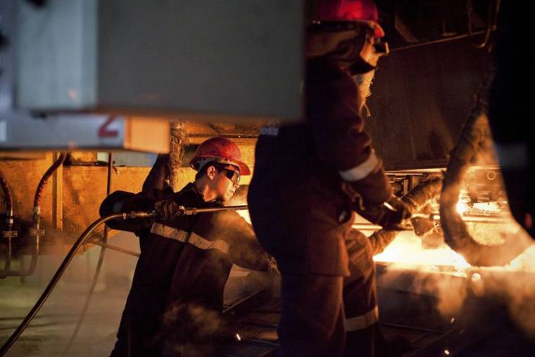 Des employés travaillent à l'intérieur d'une machine de coulée continue dans l'aciérie ArcelorMittal Temirtau à Temirtau