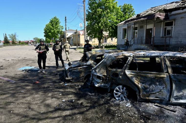 Des policiers ukrainiens près d'une voiture détruite par une frappe russe à  Zlotchiv, dans la région de Kharkiv, le 1er mai 2024 ( AFP / SERGEY BOBOK )