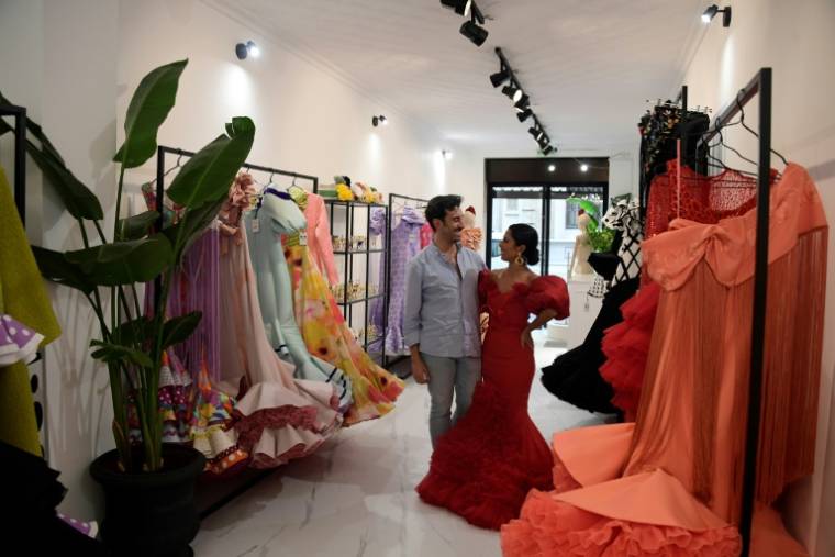 Le couturier espagnol Luis Fernandezet sa cliente Virginia Cuaresma au milieu de robes de flamenco, dans son atelier à Séville, le 8 avril 2024 ( AFP / CRISTINA QUICLER )