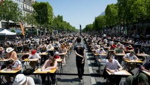 Des milliers de personnes de dix ans à 92 ans participent à une dictée géante sur l'avenue des Champs-Elysées à Paris, le 4 juin 2023  ( AFP / ALAIN JOCARD )