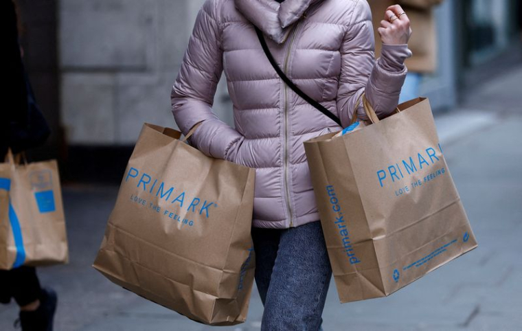 Une femme porte des sacs de shopping Primark sur Oxford Street, à Londres