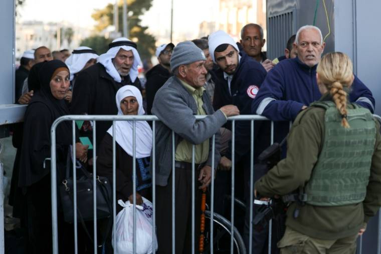 Une membre des forces de sécurité israéliennes monte la garde alors que des Palestiniens attendent derrière une barrière au point de contrôle de Bethléem, le 15 mars 2024 en Cisjordanie occupée ( AFP / HAZEM BADER )