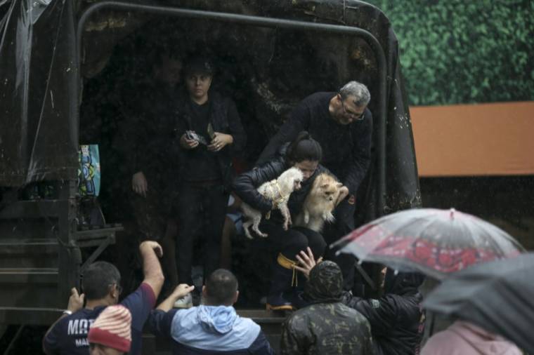 Des habitants dans un camion de l'armée après avoir été évacués de leurs logements inondés, à Sao Sebastiao do Cai, dans l'Etat du Rio Grande do Sul, le 2 mai 2024 au Brésil ( AFP / Anselmo Cunha )