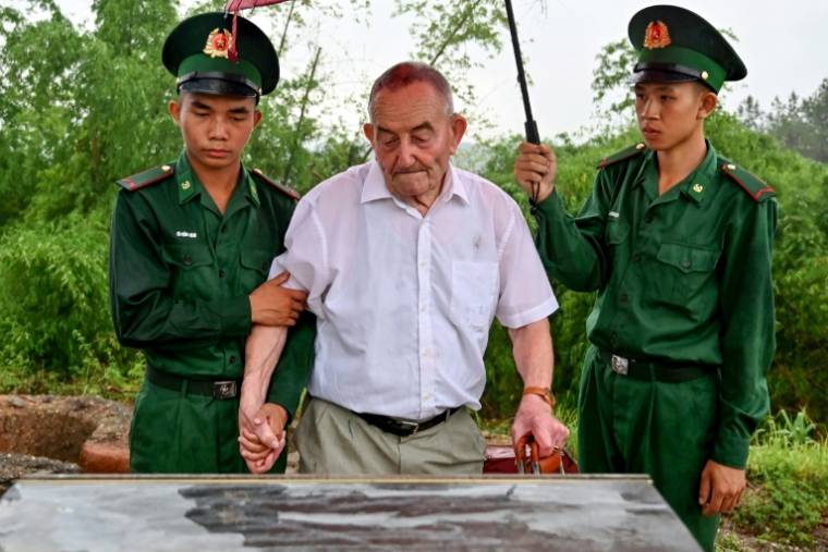 Le vétéran français Jean-Yves Guinard, aidé par des soldats vietnamiens, regarde une plaque commémorative au sommet de la colline Him Lam (colline Béatrice), le 6 mai 2024 à Dien Bien Phu ( AFP / Nhac NGUYEN )