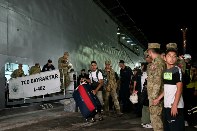 Des citoyens turcs évacués du Liban débarquent du navire de guerre turc TCG L402 Bayreaktar après son arrivée au port de Mersin, dans le sud de la Turquie, le 10 octobre 2024 ( AFP / OZAN KOSE )