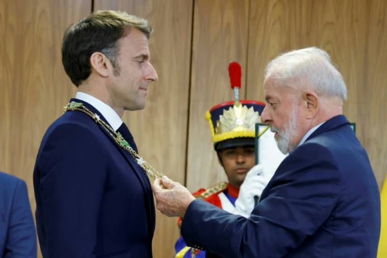Le président brésilien Luiz Inacio Lula da Silva (d) décore son homologue français Emmanuel Macron de l'Ordre national de la Croix du Sud, honneur distinguant des étrangers de marque, le 28 mars 2024 à Brasilia ( POOL / Ludovic MARIN )