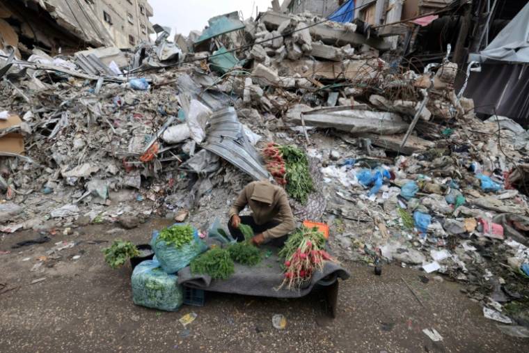 Un jeune Palestinien vend des légumes devant un bâtiment détruit par un bombardement israélien à Rafah, dans le sud de la bande de Gaza, le 7 avril 2024 ( AFP / MOHAMMED ABED )