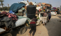 Des déplacés palestiniens en chemin vers le nord de Gaza  poussent une voiture surchargée, à Nousseirat, le 28 janvier 2025 ( AFP / Eyad BABA )