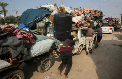 Des déplacés palestiniens en chemin vers le nord de Gaza  poussent une voiture surchargée, à Nousseirat, le 28 janvier 2025 ( AFP / Eyad BABA )