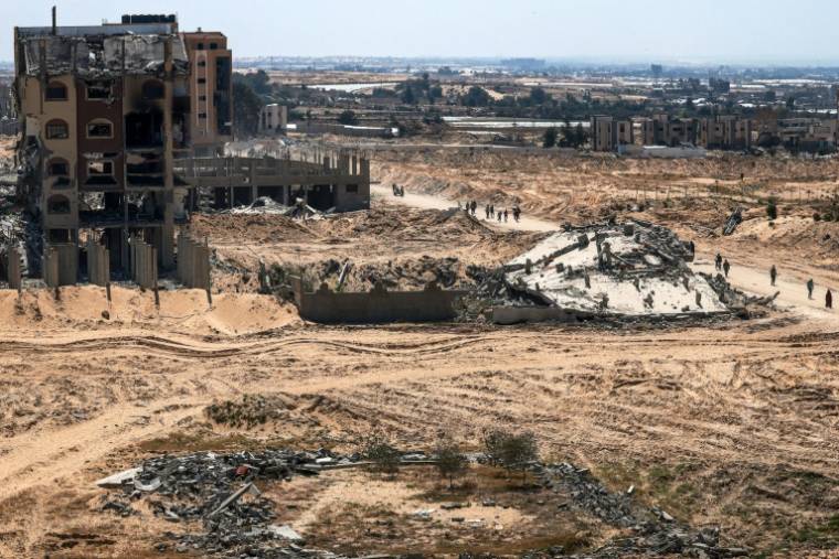 Des Palestiniens marchent au milieu de bâtiments endommagés ou détruits à Khan Younès après le retrait des troupes israéliennes de cette ville du sud de la bande de Gaza, le 7 avril 2024 ( AFP / MOHAMMED ABED )