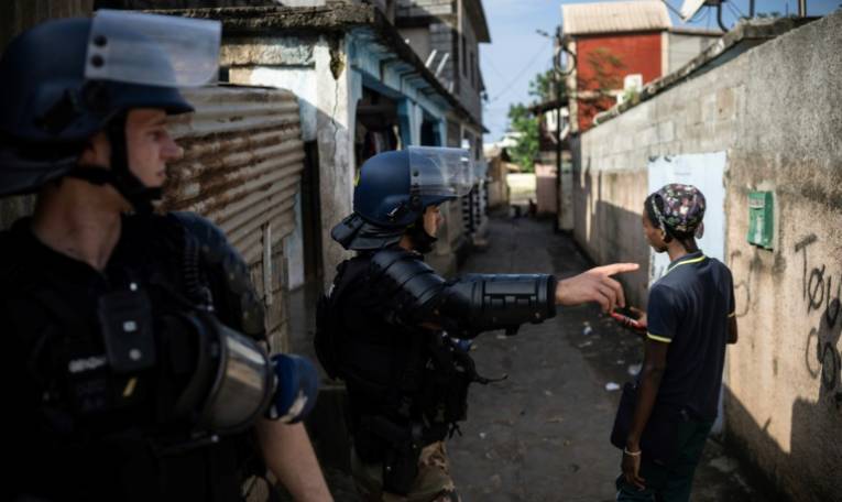Des gendarmes contrôlent un jeune garçon lors d'une opération de sécurité dans un bidonville à  Koungou, à Mayotte, le 16 février 2024 ( AFP / JULIEN DE ROSA )