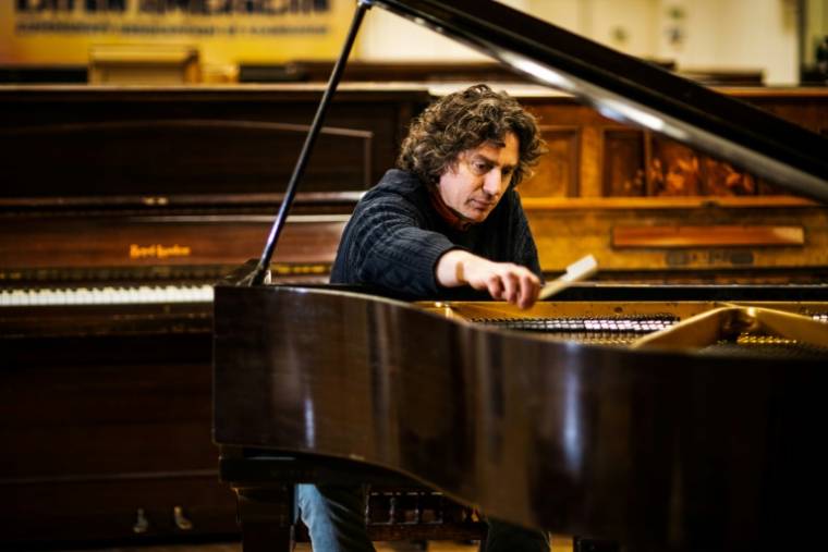 Le musicien Tim Vincent-Smith, co-directeur de "Pianodrome", accorde un piano qui a été restauré, le 9 février 2023 à Edimbourg, en Ecosse ( AFP / Andy Buchanan )