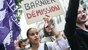 Une femme porte une pancarte demandant la démission du Premier ministre Michel Barnier à Nantes le 7 septembre 2024 ( AFP / Sebastien Salom-Gomis )