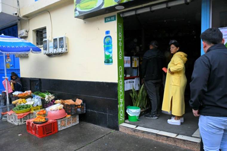 Des clients dans un magasin plongé dans la pénombre en raison des rationnements d'électricité, le 19 avril 2024 à Quito, en Equateur ( AFP / Rodrigo BUENDIA )