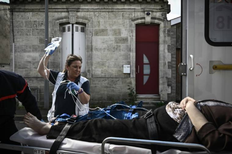 Pascale Martinet, infirmière anesthésiste et membre de l'une des premières unités hospitalières mobiles paramédicales (UMH-P) du CHU de Bordeaux, s'occupe d'une femme transportée vers une clinique suite à un appel d'urgence, le 17 avril 2024  ( AFP / Philippe LOPEZ )