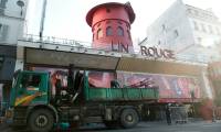 Des ouvriers sécurisent la zone devant le Moulin Rouge à Paris après que ses ailes et des lettres de la façade sont tombées dans la nuit sans faire de blessés, le 25 avril 2024 ( AFP / Geoffroy VAN DER HASSELT )