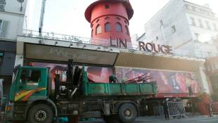 Des ouvriers sécurisent la zone devant le Moulin Rouge à Paris après que ses ailes et des lettres de la façade sont tombées dans la nuit sans faire de blessés, le 25 avril 2024 ( AFP / Geoffroy VAN DER HASSELT )