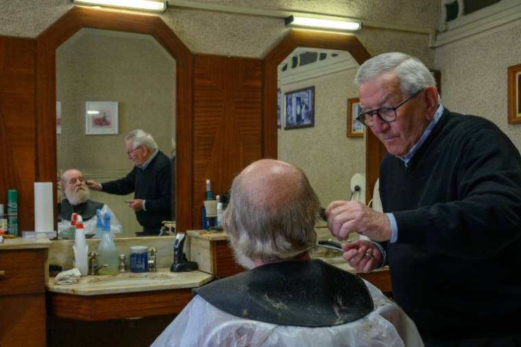 Le coiffeur Roger Amilhastre (D), âgé de 90 ans, dans son salon à Saint-Girons, en Ariège, le 16 avril 2024  ( AFP / Ed JONES )