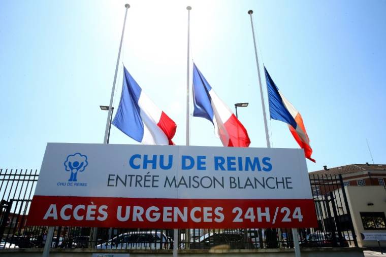 Drapeaux tricolores en berne à l'entrée de l'hôpital de Reims où a été mortellement blessée une infirmière, le 24 mai 2023 ( AFP / FRANCOIS NASCIMBENI )