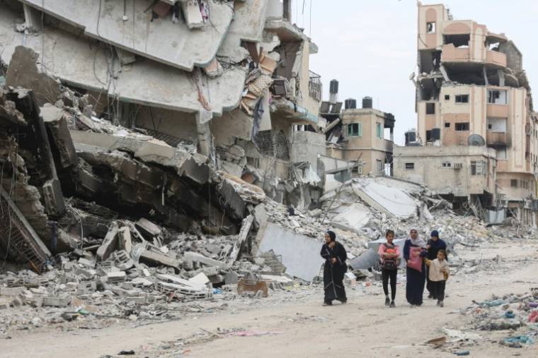 Des Palestiniens marchent le 8 avril 2024 entre des bâtiments détruits par des bombardements israéliens dans la ville de Gaza, dans le nord du territoire palestinien où une guerre oppose Israël au mouvement islamiste palestinien ( AFP / - )