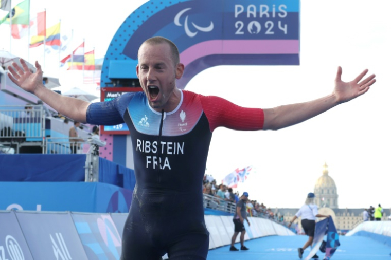 Le Français Jules Ribstein célèbre son titre paralympique en triathlon (catégorie PTS2) le 2 septembre 2024 à Paris ( AFP / ALAIN JOCARD )