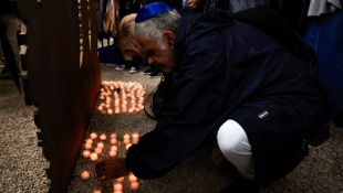 Une personne dépose une bougie devant une œuvre d'art commémorative dévoilée lors d'une cérémonie d'hommage aux victimes de l'attaque du 7 octobre contre Israël par le Hamas à Nice, le 7 octobre 2024 ( AFP / Valery HACHE )