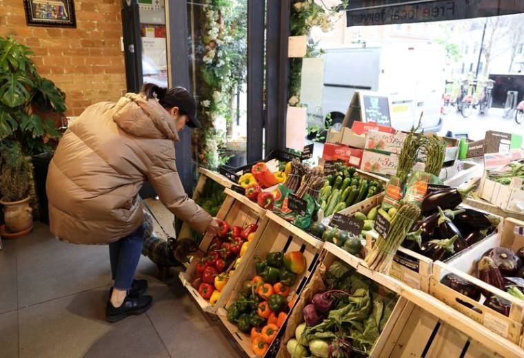 Une cliente achète des légumes à l'épicerie fine Andreas, à Londres