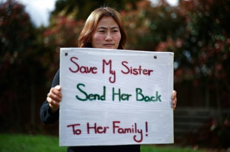 Kim Kyu-li tient une pancarte "Sauvez ma soeur, rendez-la à sa famille", le 25 mars 2024 à Londres ( AFP / Henry NICHOLLS )