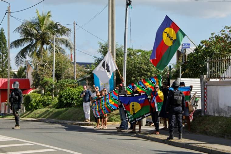 Des manifestants avec des drapeaux kanak sur le parcours du cortège du président de la République Emmanuel Macron à Nouméa, en Nouvelle-Calédonie, le 23 mai 2024 ( POOL / Ludovic MARIN )