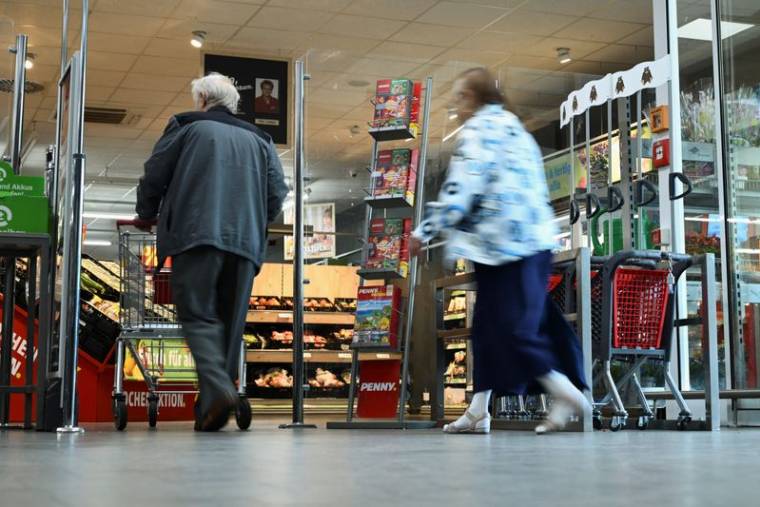 Des personnes passent devant un stand faisant référence à la campagne européenne "coûts réels" menée chaque semaine par le supermarché discount Penny à Berlin