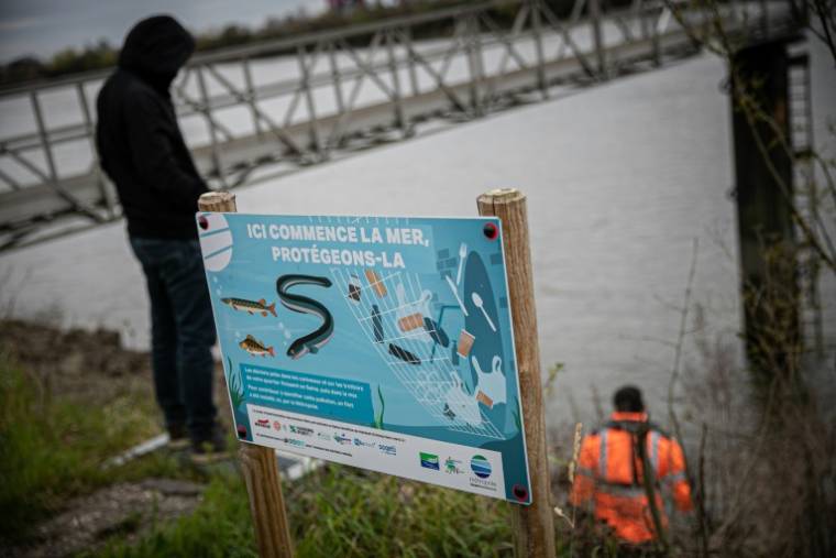 "Ici, commence la mer, protégeons-là": le long de la Seine, à Rouen une affiche invite à protéger le fleuve de la pollution, le 28 mars 2023 ( AFP / Lou BENOIST )