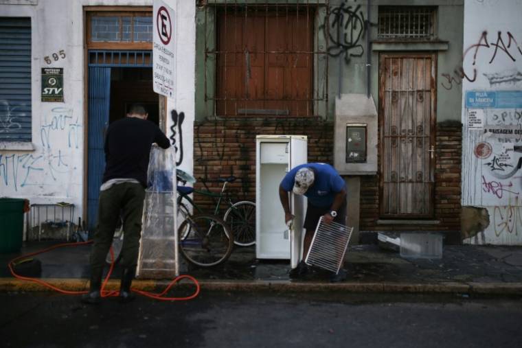 Des vendeurs nettoient leurs produits après les inondations qui ont touché leurs magasins dans le quartier à Porto Alegre, dans l'État du Rio Grande do Sul, au Brésil, le 14 mai 2024 ( AFP / Anselmo Cunha )