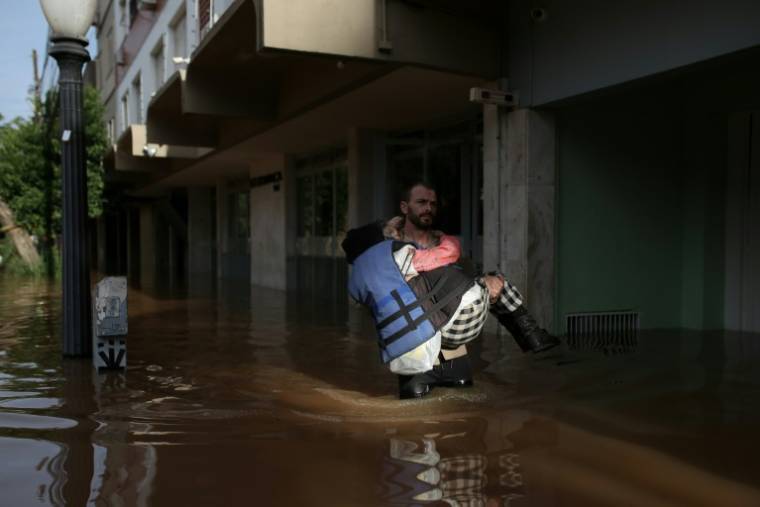 Un volontaire porte une habitante évacuée de son domicile dans une zone inondée de Porto Alegre, dans l'Etat du Rio Grande do Sul, le 8 mai 2024 au Brésil ( AFP / Anselmo CUNHA )