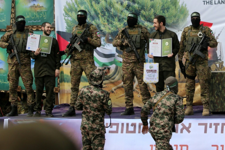 L'otage israélien Eliya Cohen (G) et Omer Shem Tov exhibés sur un podium lors de leur libération par le Hamas à Nousseirat, le 22 février 2025 ( AFP / Eyad BABA )