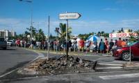 Des habitants font la queue pour acheter des provisions dans un supermarché, à côté des restes incendiés des incidents de la nuit, dans le quartier de Magenta à Nouméa, en Nouvelle Calédonie le 18 mai 2024 ( AFP / Delphine Mayeur )