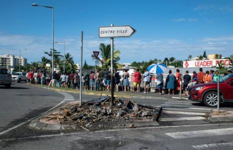 Des habitants font la queue pour acheter des provisions dans un supermarché, à côté des restes incendiés des incidents de la nuit, dans le quartier de Magenta à Nouméa, en Nouvelle Calédonie le 18 mai 2024 ( AFP / Delphine Mayeur )