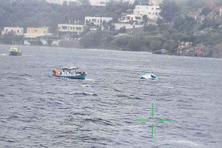 Un bateau de pêche s'approche d'un bateau pneumatique à moitié coulé qui transportait des migrants au large de l'île de Leros