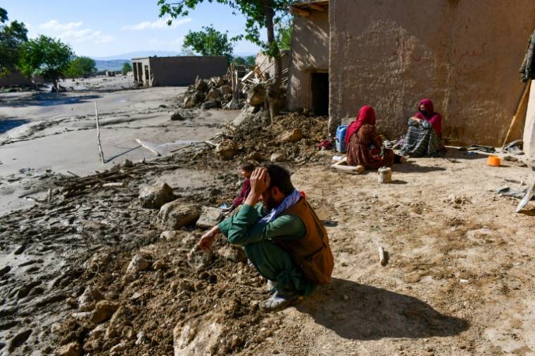 Des Afghans sont assis devant leur maison endommagée après les inondations dans le district de Burka, dans la province de Baghlan, au nord du pays, le 12 mai 2024 ( AFP / Atif ARYAN )