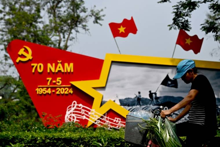 Une femme à vélo passe à Hanoï, le 25 avril 2024, devant une structure commémorant 70ème anniversaire de la victoire de Dien Bien Phu contre les troupes françaises, qui a conduit à l'émergence du  Vietnam indépendant.  ( AFP / Nhac NGUYEN )
