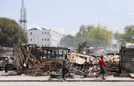 Des gens passent devant les restes de véhicules incendiés par des gangs, à Port-au-Prince