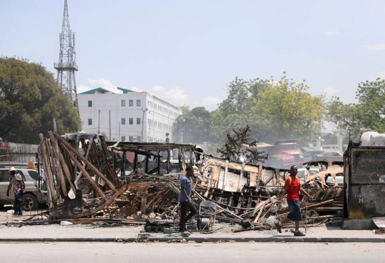 Des gens passent devant les restes de véhicules incendiés par des gangs, à Port-au-Prince